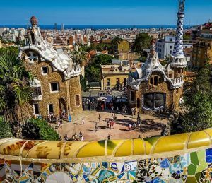Admira el colorido banco de mosaicos del Parque Güell, con la arquitectura de Gaudí y el horizonte de Barcelona de fondo. Enriquece tu visita explorando más maravillas de Barcelona con la Barcelona City Pass. - ForTwo - Planes para parejas