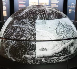 La experiencia inmersiva "Dragones y Modernismo en Barcelona" presenta una cúpula con patrones abstractos blancos y mapas en un espacio de exposición oscuro, capturando el espíritu artístico del estilo modernista de Barcelona. - ForTwo - Planes para parejas