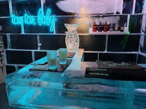 Disfrute del ambiente romántico de ICEBARCELONA con su letrero de neón brillante y su barra de hielo. Disfrute de exquisitas bebidas, rodeado de botellas brillantes en los estantes, para una experiencia perfecta con el Pack Romántico en ICEBARCELONA. - ForTwo - Planes para parejas
