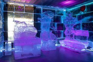 Las fascinantes esculturas de hielo, bañadas por una luz púrpura y azul, crean un ambiente deslumbrante con intrincados tallados sobre una pared texturizada que evocan el arte de ICEBARCELONA. Es una experiencia inigualable que ofrece el Pack Romántico en ICEBARCELONA. - ForTwo - Planes para parejas