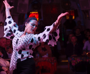 En medio del animado ambiente de Los Tarantos, un bailaor de flamenco encarna la tradición, actuando apasionadamente con lunares como parte del Espectáculo Flamenco en las Cuevas del Sacromonte con Los Tarantos. - ForTwo - Planes para parejas
