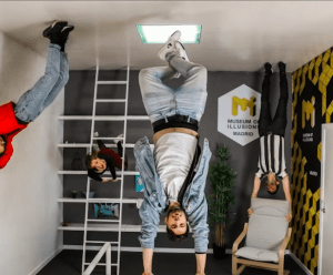 Cuatro personas aparecen boca abajo en el Museo de las Ilusiones de Madrid, creando una divertida ilusión óptica. Los visitantes pueden disfrutar de esta peculiar atracción adquiriendo Entradas al Museo de las Ilusiones de Madrid para explorar las fascinantes exposiciones. - ForTwo - Planes para parejas