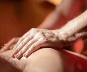 Primer plano de unas manos proporcionando un Entradas para Hammam Al Ándalus Granada con masaje exclusivo en la espalda de una persona, bajo una iluminación cálida. - ForTwo - Planes para parejas