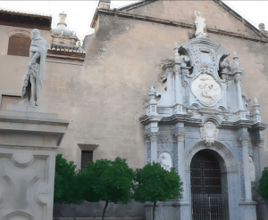 La ornamentada fachada de piedra del edificio, que evoca la Granada poética de García Lorca, presenta estatuas y tallas intrincadas, mientras que los árboles en primer plano invitan a un "Federico García Lorca: Tour guiado por Granada" a través de su belleza atemporal. - ForTwo - Planes para parejas
