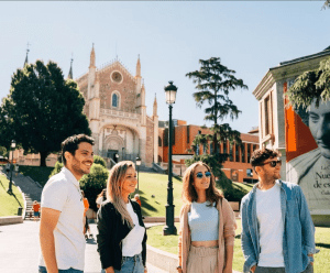 Cuatro personas sonriendo al aire libre cerca del histórico Museo del Prado, disfrutando de un día soleado en Madrid, mientras realizan la "Madrid y Toledo: Excursión guiada de un día y Museo del Prado" rodeada de árboles. - ForTwo - Planes para parejas