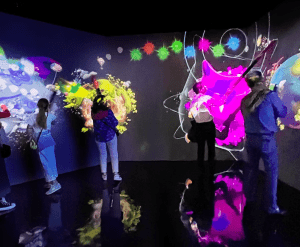 Los visitantes exploran arte digital abstracto y colorido en pantallas grandes con Entradas al Nomad Museo Inmersivo, creando una experiencia de museo encantadora. - ForTwo - Planes para parejas