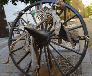 Un esqueleto sobre una gran rueda de carreta de madera crea una escena inquietante similar al Palacio de los Olvidados, donde las Entradas sin colas al Palacio de los Olvidados garantizan un acceso perfecto a sus cautivadoras exposiciones. - ForTwo - Planes para parejas