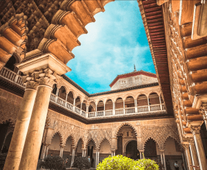 Sevilla Super Combi captura la belleza de un ornamentado patio sevillano con sus elegantes arcos, elegantes columnas y diseños intrincados contra un cielo azul vibrante. - ForTwo - Planes para parejas