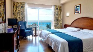 Disfrute de una escapada con desayuno en el Hotel Soho Boutique Las Vegas de Málaga. Esta acogedora habitación cuenta con dos cómodas camas, vistas al mar, un amplio ventanal, televisor, silla y cortinas decorativas para un refugio encantador. - ForTwo - Planes para parejas