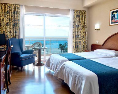 Disfrute de una escapada con desayuno en el Hotel Soho Boutique Las Vegas de Málaga. Esta acogedora habitación cuenta con dos cómodas camas, vistas al mar, un amplio ventanal, televisor, silla y cortinas decorativas para un refugio encantador. - ForTwo - Planes para parejas