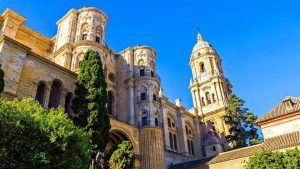 El Hilton Garden Inn en Málaga ofrece una escapada premium, ubicado entre catedrales históricas con una arquitectura ornamentada y árboles altos bajo un cielo azul claro, brindando una visión del rico pasado de Málaga. - ForTwo - Planes para parejas