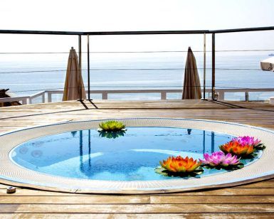 Disfrute de una "Escapada en Torremolinos con Suite 4 estrellas: Roc Lago Rojo" con piscina redonda en una terraza de madera con flores de loto flotantes, vistas al mar y relajación a la sombra de una sombrilla. - ForTwo - Planes para parejas