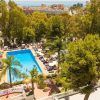 Vista aérea de una piscina rodeada de árboles y tumbonas, con vistas a la ciudad y al mar: un lugar perfecto para una pareja en una Escapada a Torremolinos en pareja con todo incluido. - ForTwo - Planes para parejas