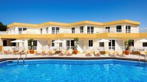 Descubre los encantadores Checkin Bungalows Atlántida en Tenerife, con alojamientos de dos plantas con vibrantes detalles en amarillo y lujosas tumbonas y sombrillas junto a una gran piscina, ideal para una escapada en pareja. - ForTwo - Planes para parejas