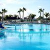 Descubre el encanto de Escapada, un resort en Lanzarote, en Playa Blanca: Hotel THB Tropical Island. Relájate en una piscina al aire libre con tobogán azul, palmeras y un puente panorámico, todo bajo un cielo despejado. - ForTwo - Planes para parejas