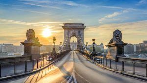Al amanecer, el Puente de las Cadenas de Budapest ofrece vistas impresionantes con majestuosas estatuas de leones de piedra que custodian el camino bajo un cielo azul despejado. A pocos pasos, Escapada de fin de semana a Budapest: Prestige Hotel garantiza una escapada de fin de semana inolvidable. - ForTwo - Planes para parejas
