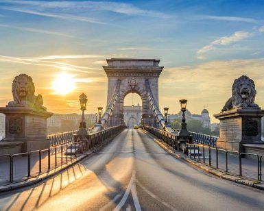 Al amanecer, el Puente de las Cadenas de Budapest ofrece vistas impresionantes con majestuosas estatuas de leones de piedra que custodian el camino bajo un cielo azul despejado. A pocos pasos, Escapada de fin de semana a Budapest: Prestige Hotel garantiza una escapada de fin de semana inolvidable. - ForTwo - Planes para parejas
