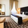El Hotel Buda Castle Fashion, en el centro de Budapest, ofrece una habitación moderna con cama doble, sillón, espejo grande, alfombra texturizada e iluminación cálida. - ForTwo - Planes para parejas
