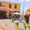 Un pequeño hotel con una fachada amarilla, asientos al aire libre y un letrero que dice Hotel El Tejar bajo el cielo azul de Tenerife, ideal para una "Escapada en pareja a Tenerife: spa, vistas al mar y cava". - ForTwo - Planes para parejas