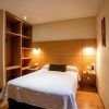 Cómoda habitación en Escapada en el centro de Córdoba: hotel Serrano con cama doble, estanterías de madera, iluminación cálida y una pequeña mesa con silla, ideal para tu escapada al centro de la ciudad. - ForTwo - Planes para parejas