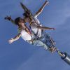 Dos personas hacen puenting en tándem, abrazándose en el aire contra el cielo azul claro y disfrutando de la emoción del "Puenting o Salto Bungee Jumping en pareja en Barcelona". - ForTwo - Planes para parejas