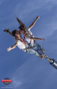 Dos personas hacen puenting en tándem, abrazándose en el aire contra el cielo azul claro y disfrutando de la emoción del "Puenting o Salto Bungee Jumping en pareja en Barcelona". - ForTwo - Planes para parejas