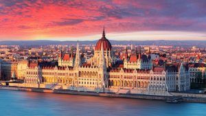 Mientras el sol se pone sobre Budapest durante "Un fin de semana en Budapest", el edificio del Parlamento húngaro ilumina un cielo impresionante, con sus reflejos brillando en el río Danubio. - ForTwo - Planes para parejas