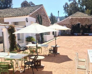 El patio exterior cuenta con mesas, sillas y sombrillas, perfecto para un día soleado. Ubicado entre rústicos edificios de piedra, es ideal para una cena romántica durante su escapada de 2 noches + cena romántica + hammam (Córdoba) al encantador entorno. - ForTwo - Planes para parejas