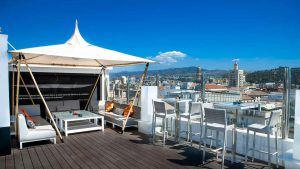 Disfruta de una "Escapada en el Hotel Soho Bahía de Málaga con desayuno" en el bar de la azotea, con elegantes asientos y una marquesina blanca, y con impresionantes vistas de la ciudad. Perfecto bajo un cielo azul despejado después del desayuno. - ForTwo - Planes para parejas