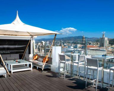 Disfruta de una "Escapada en el Hotel Soho Bahía de Málaga con desayuno" en el bar de la azotea, con elegantes asientos y una marquesina blanca, y con impresionantes vistas de la ciudad. Perfecto bajo un cielo azul despejado después del desayuno. - ForTwo - Planes para parejas