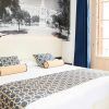 Descubra Escapada en el Hotel Soho Boutique (Málaga) en esta elegante habitación con una gran cama decorada con ropa de cama de diseño geométrico, un sillón y un distintivo mural en blanco y negro. Un acogedor refugio para su escapada a Málaga, enclavado en el corazón de la elegancia. - ForTwo - Planes para parejas