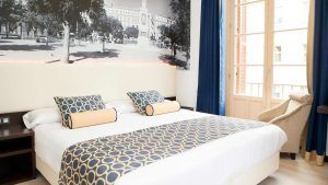 Descubra Escapada en el Hotel Soho Boutique (Málaga) en esta elegante habitación con una gran cama decorada con ropa de cama de diseño geométrico, un sillón y un distintivo mural en blanco y negro. Un acogedor refugio para su escapada a Málaga, enclavado en el corazón de la elegancia. - ForTwo - Planes para parejas