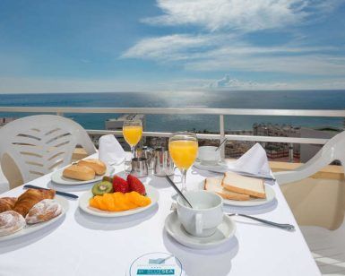 Disfrute de un desayuno sereno en un balcón con vistas al mar en Torremolinos, con frutas, bollería, tostadas y zumo de naranja sobre un mantel blanco impecable. La "Escapada de 3 días con todo incluido en Torremolinos" le garantiza tranquilidad y sabor para empezar el día con buen pie. - ForTwo - Planes para parejas