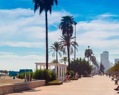 El paseo marítimo de Fuengirola, con sus palmeras y bancos, ofrece vistas pintorescas y es ideal para una vibrante escapada de fin de semana. Disfrute de un alojamiento práctico en los cercanos Apartamentos Mediterráneo Real, "Escapada de fin de semana a Fuengirola". - ForTwo - Planes para parejas