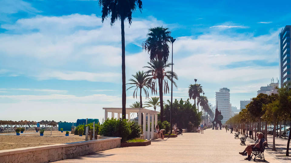 El paseo marítimo de Fuengirola, con sus palmeras y bancos, ofrece vistas pintorescas y es ideal para una vibrante escapada de fin de semana. Disfrute de un alojamiento práctico en los cercanos Apartamentos Mediterráneo Real, "Escapada de fin de semana a Fuengirola". - ForTwo - Planes para parejas