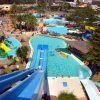 La vista aérea del Parque Acuático, cerca del hotel Las Palmeras, muestra toboganes vibrantes, piscinas cristalinas, palmeras exuberantes y visitantes disfrutando de las atracciones en la Escapada a Fuengirola con entradas al Parque Acuático. - ForTwo - Planes para parejas