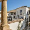 El patio blanco de estilo español de Escapada a Córdoba en el barrio judío, con balcones arqueados y techos de tejas, ofrece un refugio encantador bajo un cielo despejado, evocando el encanto de los barrios de Córdoba. - ForTwo - Planes para parejas