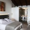 La Escapada en una casa señorial del siglo XVIII del Hotel La Casa del Médico en Córdoba ofrece una moderna habitación con cama doble, sábanas blancas, decoración artística y un baño abierto con paredes de cristal que realzan su elegante encanto. - ForTwo - Planes para parejas