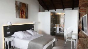 La Escapada en una casa señorial del siglo XVIII del Hotel La Casa del Médico en Córdoba ofrece una moderna habitación con cama doble, sábanas blancas, decoración artística y un baño abierto con paredes de cristal que realzan su elegante encanto. - ForTwo - Planes para parejas