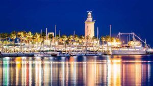 Por la noche, el puerto deportivo de Málaga, con un faro iluminado, yates y luces reflectantes en aguas tranquilas, ofrece una escapada perfecta al centro de Málaga con una estancia en el Hotel Sallés de 4 estrellas. - ForTwo - Planes para parejas