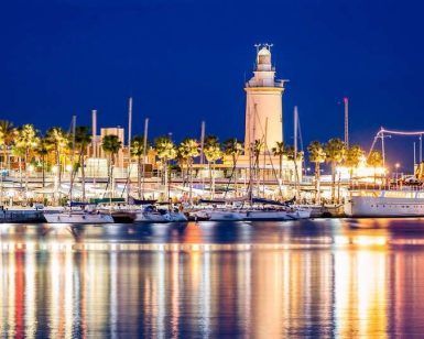 Por la noche, el puerto deportivo de Málaga, con un faro iluminado, yates y luces reflectantes en aguas tranquilas, ofrece una escapada perfecta al centro de Málaga con una estancia en el Hotel Sallés de 4 estrellas. - ForTwo - Planes para parejas