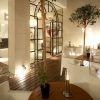 La moderna cafetería interior del Hotel Taburiente en Tenerife ofrece sillas blancas, mesas de madera, exuberantes plantas en macetas y una cálida iluminación. Grandes puertas de cristal dan la bienvenida a la luz natural en el corazón de la ciudad. - ForTwo - Planes para parejas