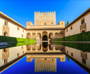Bajo un cielo azul claro, descubra la piscina reflectante, el arco y la torre de los Palacios Nazaríes de la Alhambra con Entradas para Alhambra y Palacios Nazaríes: Visita guiada. - ForTwo - Planes para parejas