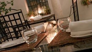 Restaurante Azahar (Sevilla) ofrece una elegante experiencia gastronómica con cristalería, servilletas blancas, manteles individuales tejidos y una linterna de vela, creando el ambiente perfecto de Sevilla. - ForTwo - Planes para parejas