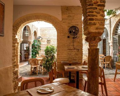 En Córdoba, Bodegas Mezquita ofrece un encantador ambiente rústico con arcos de piedra, mesas de madera y sillas de mimbre bajo una cálida iluminación. Es el entorno acogedor perfecto para disfrutar del exquisito menú Alcázar en su "Oferta: cena para dos". - ForTwo - Planes para parejas