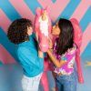 En una sala con dibujos en zigzag del Museo Big Fun Barcelona, adquirida con las entradas del Museo Big Fun Barcelona, dos personas besan una estatua de un unicornio rosa cubierta de crema batida. - ForTwo - Planes para parejas