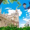 Experimente una vista impresionante de la icónica torre de la Giralda de la Catedral de Sevilla con su "Entrada para la Catedral de Sevilla y la Giralda (sin colas)", con un cielo azul como telón de fondo, una exuberante vegetación y acompañada de una encantadora farola vintage. - ForTwo - Planes para parejas