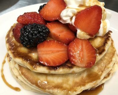 El Gastro-brunch en Enkel Barcelona consiste en una deliciosa pila de panqueques cubiertos con fresas frescas, moras, crema batida y almíbar, perfecto para una mañana tranquila. - ForTwo - Planes para parejas