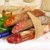 Un paquete de arpillera con una variedad de embutidos capturados captura el encanto rústico del Cercado de la Alpujarra, mientras que el pimiento verde, el ajo, el aceite de oliva y el vino evocan una experiencia de Menú a la carta en el Cercado de la Alpujarra. - ForTwo - Planes para parejas