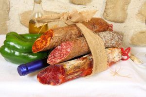 Un paquete de arpillera con una variedad de embutidos capturados captura el encanto rústico del Cercado de la Alpujarra, mientras que el pimiento verde, el ajo, el aceite de oliva y el vino evocan una experiencia de Menú a la carta en el Cercado de la Alpujarra. - ForTwo - Planes para parejas